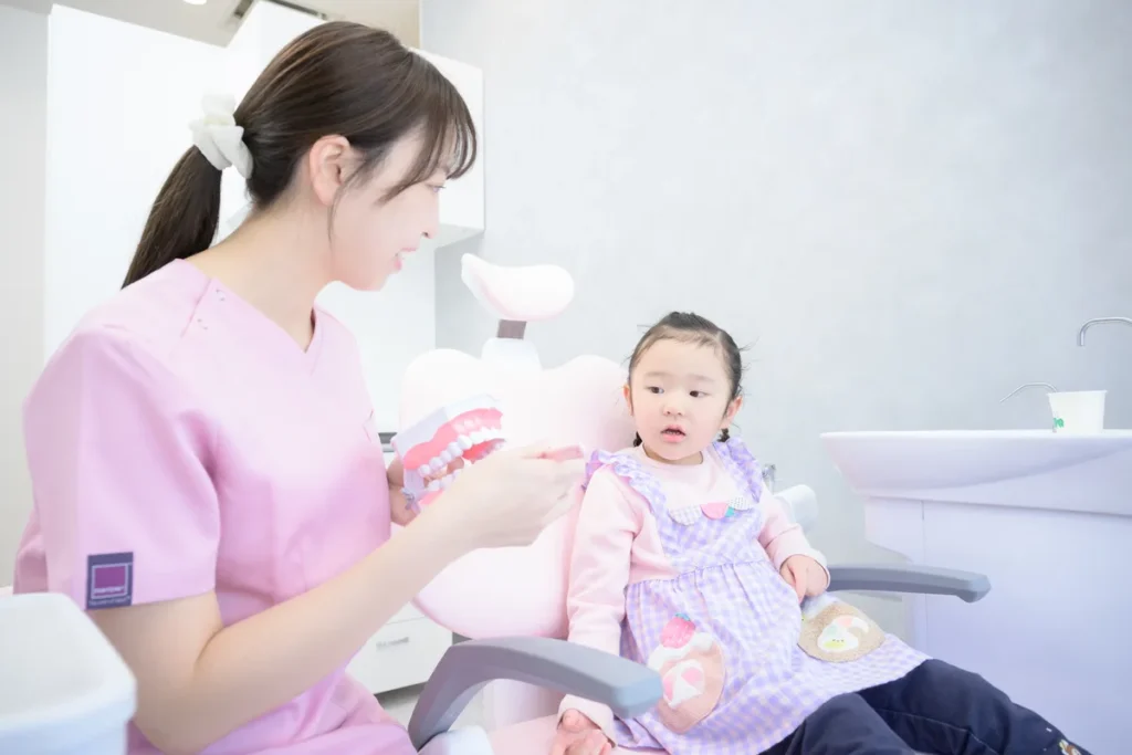 診療台で歯科衛生士が子どもに優しく声をかけている様子